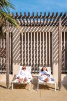 two people are laying in chairs on the beach at Hôtel Helios &amp; SPA - Ile des Embiez in Six-Fours-les-Plages