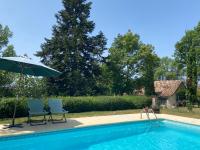 two chairs and an umbrella next to a swimming pool at Gîte de charme avec grand jardin &amp; piscine in Touffailles