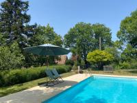 an umbrella and two chairs next to a swimming pool at Gîte de charme avec grand jardin &amp; piscine in Touffailles