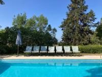 a group of chairs and an umbrella next to a pool at Gîte de charme avec grand jardin &amp; piscine in Touffailles