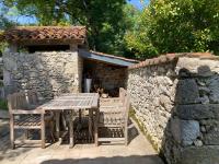 a table and chairs in front of a stone wall at Gîte de charme avec grand jardin &amp; piscine in Touffailles