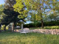 a bench sitting in the grass next to a stone wall at Gîte de charme avec grand jardin &amp; piscine in Touffailles