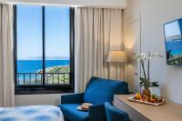 a hotel room with a blue chair and a table with a room with a view at Hôtel Helios &amp; SPA - Ile des Embiez in Six-Fours-les-Plages