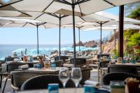 un restaurante con mesas y sillas con sombrillas en Tiara Miramar Beach Resort, en Théoule-sur-Mer