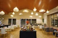 Un comedor con mesas, sillas y luces. en Front One Hotel Sragen, en Sragen