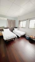 two beds in a room with wooden floors and windows at Sun B&amp;B in Taitung City