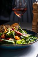 a plate of food with a salad and a glass of wine at Europa Royale Bucharest in Bucharest