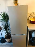 a refrigerator is standing next to a table at No 25 superbe apartment plein centre calme ,Netflix in Mirepoix