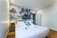 a bedroom with a white bed with a painting on the wall at ALOE KEYWEEK Architect Apartment with terrace and garage Biarritz in Biarritz