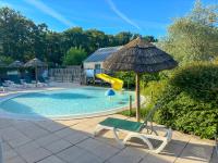 a pool with a chair and an umbrella and a slide at Camping La Mignardière in Ballan-Miré