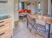 a kitchen and living room with a wooden table and chairs at Camping La Mignardière in Ballan-Miré