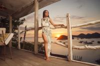 纳闽巴霍Selini Hills的一位身穿连衣裙的女子坐在绳索围栏上。