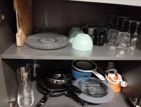 a kitchen shelf with dishes and other items on it at Le Studio de la Seine in Elbeuf