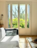 a living room with a white couch and windows at Maison familiale avec vue tour Eiffel in Suresnes