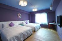 a purple bedroom with two beds and a television at Yu Sen House in Kenting
