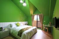 a green bedroom with a bed and a desk and a television at Yu Sen House in Kenting