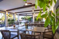 een restaurant met tafels en stoelen en een plant bij Cormoran Hotel & Residence in Villasimius