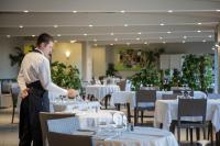 een man staat in een eetkamer met tafels bij Cormoran Hotel & Residence in Villasimius