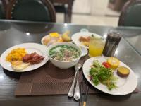 a table with plates of food and drinks on it at Paragon Noi bai Hotel & Pool in Hanoi