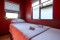 two beds in a red room with two windows at Deerpark Luxury Stays in Nairobi
