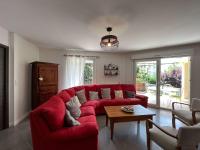 a red couch in a living room with a table at Le Jardin du Dolaizon in Le Puy-en-Velay