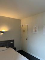 a bedroom with a white bed and a door at Hotel TGV in Quimper
