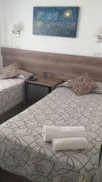 a bedroom with two beds and a painting on the wall at HOTEL ROMA DE TANDIL in Tandil