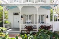 a white house with a porch with blue chairs at Ridley House - Key West Historic Inns in Key West