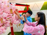 a man and a woman standing next to a tree filled with pink flowers at Uni-Resort Ku-Kuan in Heping