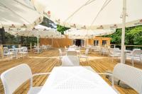 un patio con tavoli e sedie bianchi e ombrelloni di Apartamenty Leśna Przystań 2 a Węgorzewo