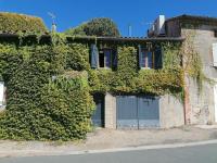 an ivy covered building with doors and windows at L’ESPRIT JANADE – GITE 4 A 6 PERSONNES. in Fénols
