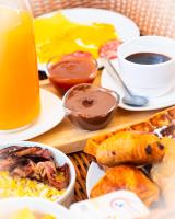 a table with plates of food and a cup of orange juice at T2 jacuzzis et piscine au centre ville de Port-Louis in Port-Louis