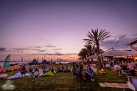 Een groep mensen zit op stoelen op het strand bij zonsondergang. bij Resort Santa Maria Hotel in Birgi Vecchi