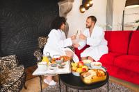 a man and woman sitting on a couch with a tray of food at Van Der Valk Sélys Liège Hotel &amp; Spa in Liège