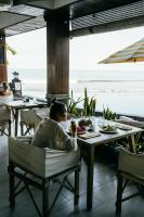 una donna seduta a un tavolo in un ristorante che guarda l'oceano di Bombora Medewi a Pulukan