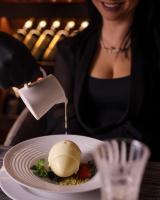 a woman is pouring sauce on a plate of food at Elexus Apartments Poiana Brasov in Poiana Brasov