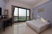 a bedroom with a bed and a desk and a large window at STSP Guest House in Xinshi