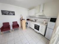a kitchen with white appliances and red chairs at GITE VENITIA T2 in Aussonne