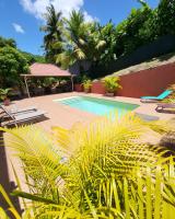 - une piscine dans une cour avec des palmiers dans l&#39;établissement Résidence Belle Anse 6 Pers 3ilets, à Les Trois-Îlets