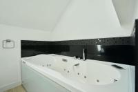 a white bath tub in a bathroom with black tiles at Loft en duplex atypique 4ch + parking in Tourcoing