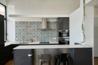 a kitchen with a counter and two stools in it at Loft en duplex atypique 4ch + parking in Tourcoing