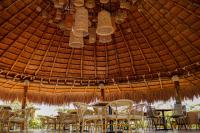 grupa stołów i krzeseł pod słomianym dachem w obiekcie GUAJIRA CASA DEL MAR w mieście Ríohacha