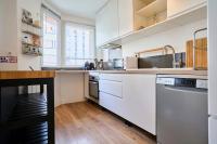 a kitchen with white cabinets and a wooden floor at Apartment balconyparking space near train station in Lille