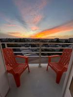 zwei rote Stühle auf einem Balkon mit Sonnenuntergang in der Unterkunft Appartement NEUF et cosy à Blois in Blois