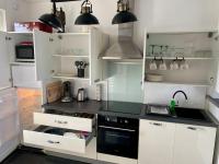 a kitchen with white cabinets and a black counter top at La Désirade by Póm in Lorient