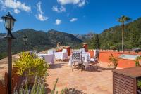 eine Terrasse mit Tischen, Stühlen und Bergen im Hintergrund in der Unterkunft Finca Es Castell in Binibona