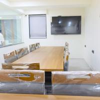 een conferentieruimte met een grote houten tafel en een scherm bij Hotel Royal Elite in Rajkot