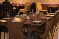 a long wooden table with chairs and wine glasses at HOBIZ Hotel in Navoi