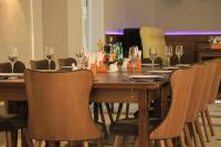 a long wooden table with chairs and wine glasses at HOBIZ Hotel in Navoi
