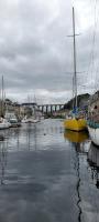 a yellow sail boat is docked in a harbor at Au Pied du Viaduc in Morlaix